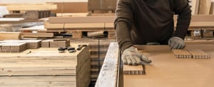 Mitarbeiter von NEXTPACK klebt Polster aus Wabenpappe in einen Transportbehälter